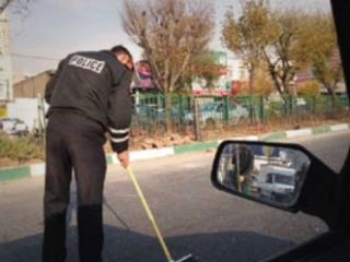 همکاری یک پلیس راهنمایی و رانندگی با رفتگر شهرداری در جارو کردن شیشه های حاصل از تصادف