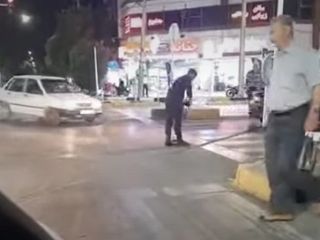 مامور وظیفه‌شناس کلانتری ۱۱ شاهین‌شهر در حال جارو کردن خرده شیشه‌های تصادف